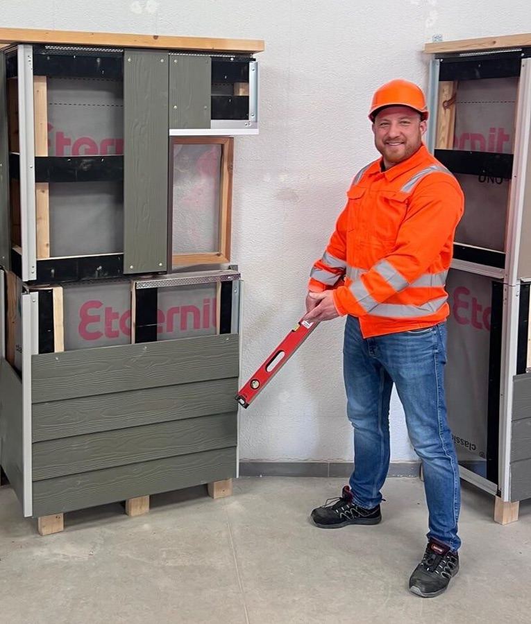 Elvis Bergs, SIA Woodenlays vadītājs, ar līmeņrādi pie fasādes apdares paraugiem