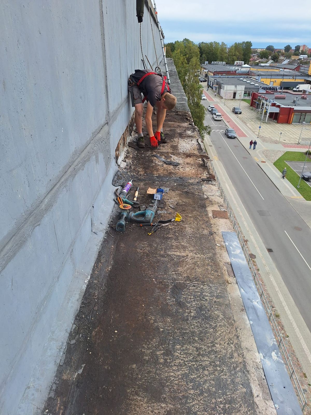 Vecā ruberoīda attīrīšana uz piecstāvu mājas balkonu jumta