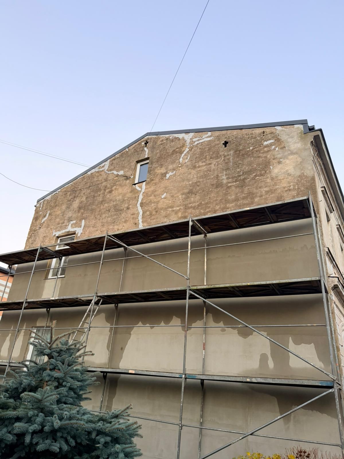 Daudzdzīvokļu mājas gala siena pirms siltināšanas, sastatnēs
