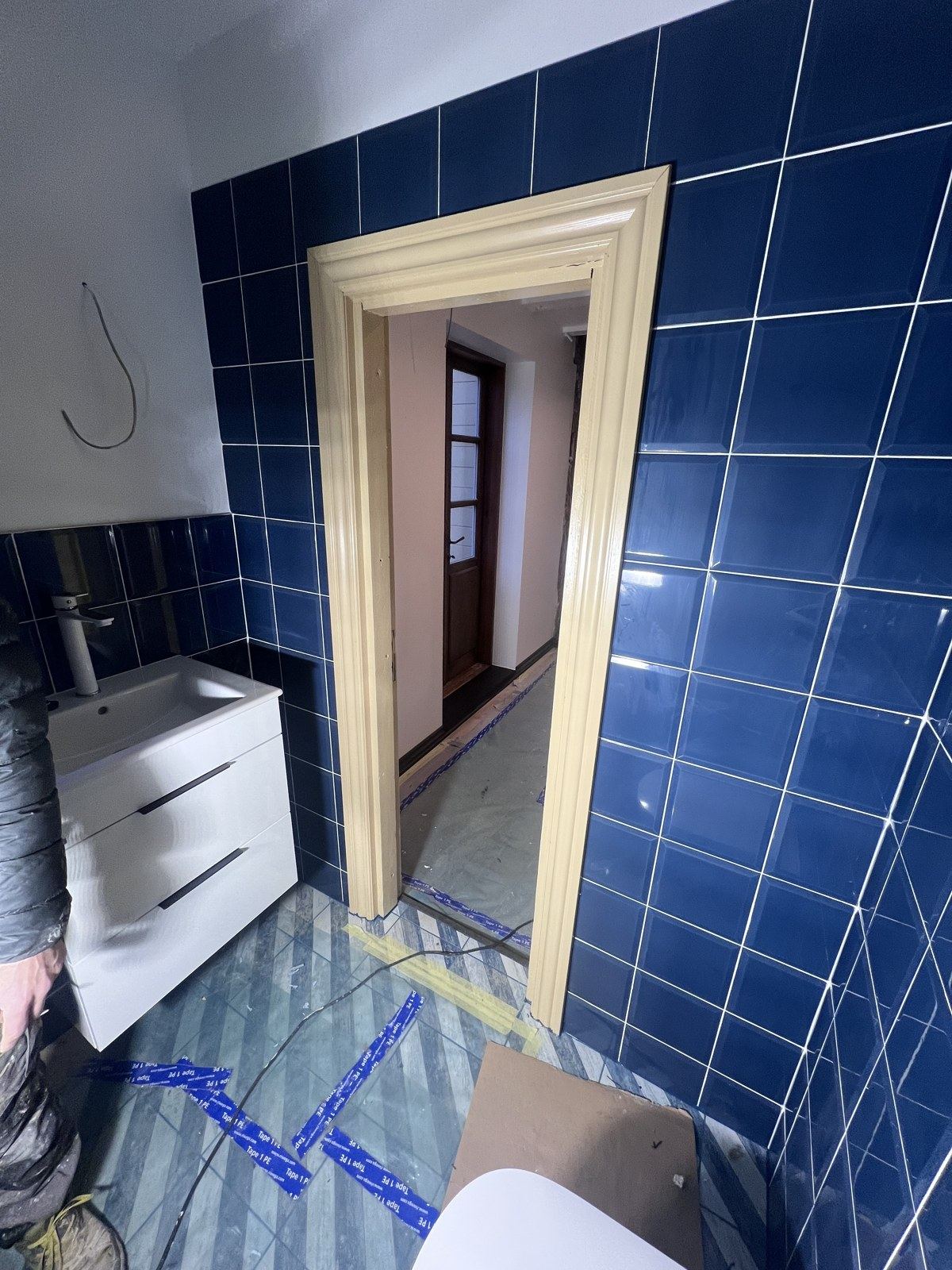 Izlietne ar skapīti, zilas flīzes un jauna durvju kārba