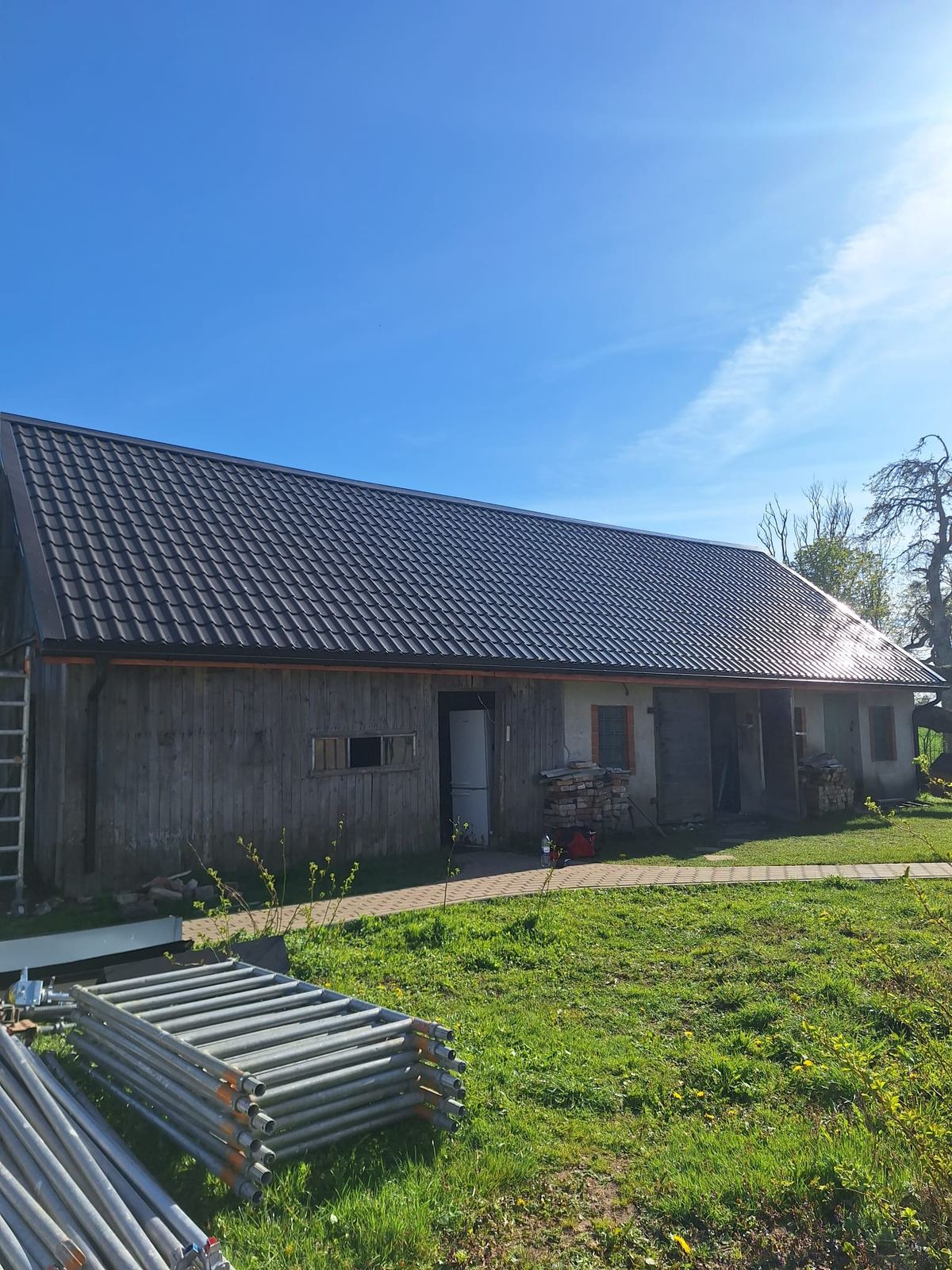 Saimniecības ēka ar jaunu tumšu metāla jumtu